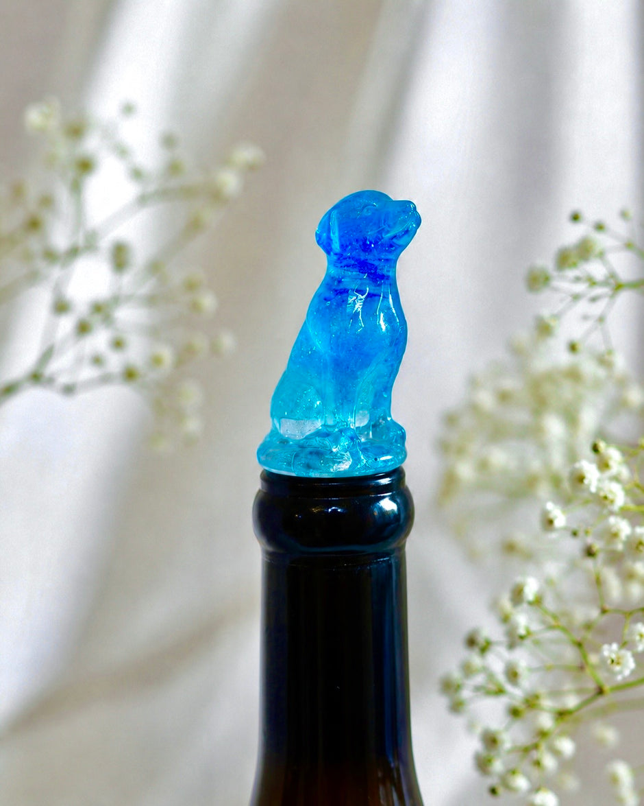 Blue dog resin wine bottle stopper displayed on a dark wine bottle